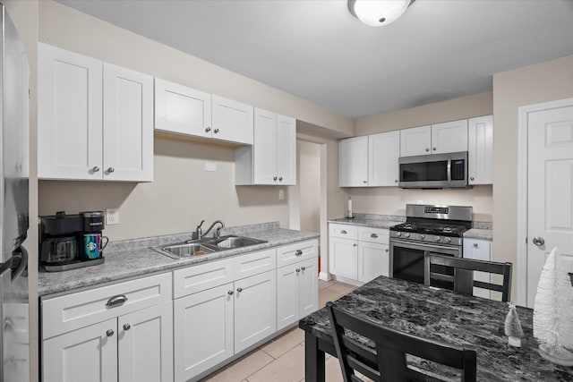 kitchen with white cabinetry, sink, light tile patterned floors, and stainless steel appliances