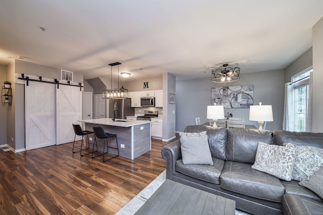 living room featuring a barn door, dark hardwood / wood-style floors, and sink