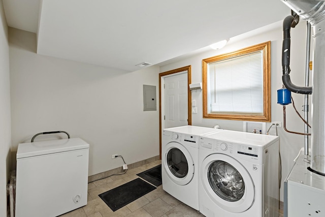 laundry room with washing machine and clothes dryer, electric panel, and light tile patterned floors