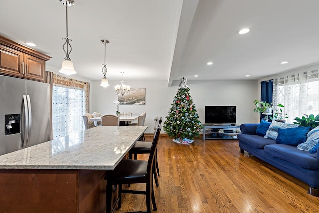 kitchen featuring dark hardwood / wood-style flooring, decorative light fixtures, light stone counters, and a wealth of natural light