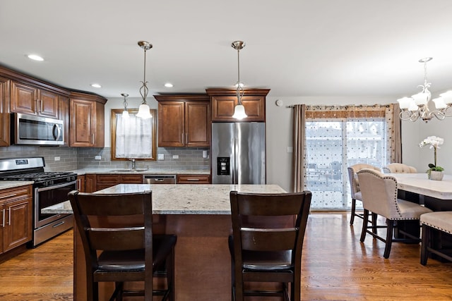 kitchen with decorative light fixtures, a center island, stainless steel appliances, and tasteful backsplash