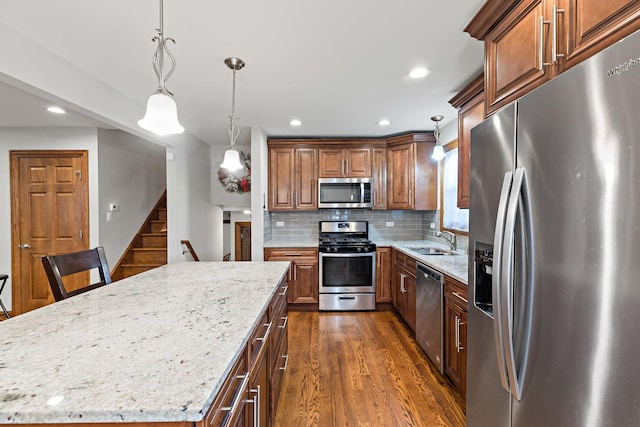 kitchen with sink, a center island, pendant lighting, decorative backsplash, and appliances with stainless steel finishes