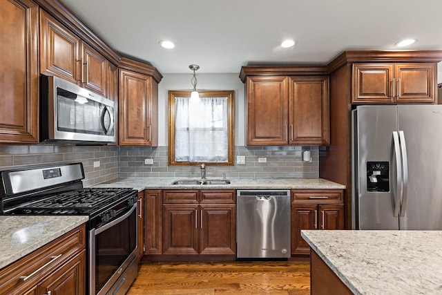 kitchen with hanging light fixtures, sink, appliances with stainless steel finishes, tasteful backsplash, and dark hardwood / wood-style flooring