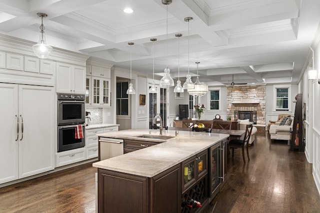 kitchen featuring decorative light fixtures, a fireplace, white cabinetry, and sink