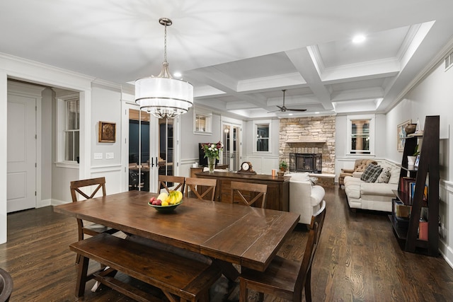 dining space featuring coffered ceiling, a stone fireplace, beamed ceiling, dark hardwood / wood-style floors, and ceiling fan with notable chandelier