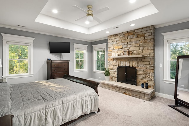 carpeted bedroom featuring a fireplace, a raised ceiling, ceiling fan, and crown molding