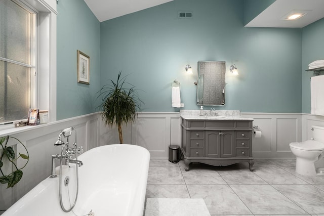 bathroom featuring tile patterned floors, vanity, vaulted ceiling, toilet, and a bathing tub