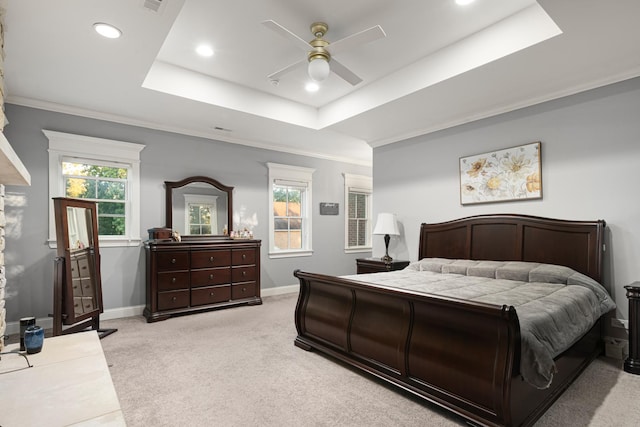 bedroom featuring ceiling fan, a raised ceiling, light carpet, and multiple windows