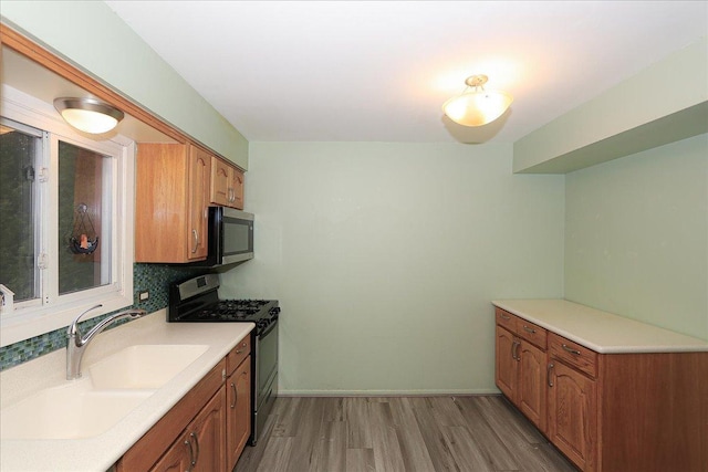 kitchen featuring backsplash, light hardwood / wood-style flooring, black range with electric stovetop, and sink