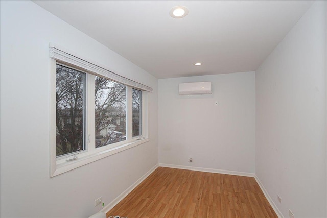 unfurnished room featuring a wall mounted AC and light hardwood / wood-style flooring