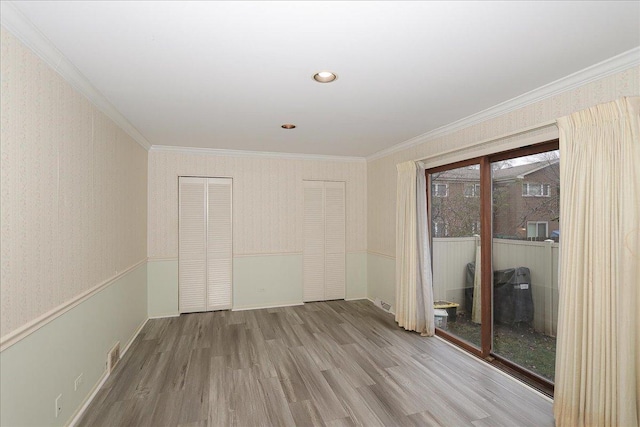 empty room with light hardwood / wood-style floors and crown molding