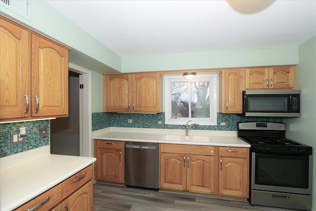 kitchen with appliances with stainless steel finishes, dark hardwood / wood-style flooring, tasteful backsplash, and sink