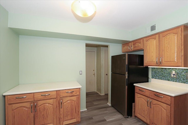 kitchen featuring hardwood / wood-style floors, refrigerator, and backsplash