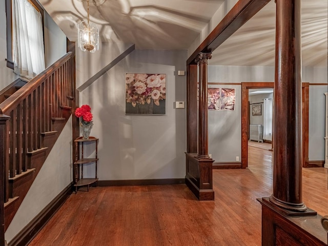 hallway with hardwood / wood-style floors, radiator heating unit, and ornate columns