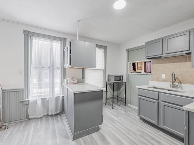 kitchen featuring gray cabinets, sink, radiator, and light hardwood / wood-style flooring