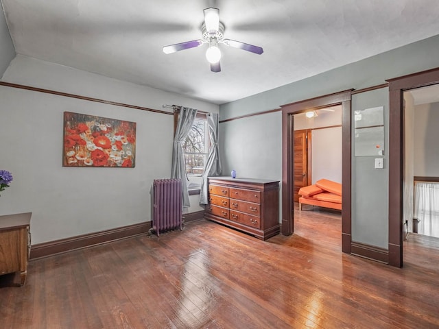 bedroom with radiator heating unit, dark hardwood / wood-style flooring, and ceiling fan