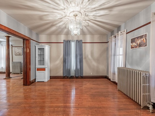 spare room with hardwood / wood-style flooring, a notable chandelier, and radiator