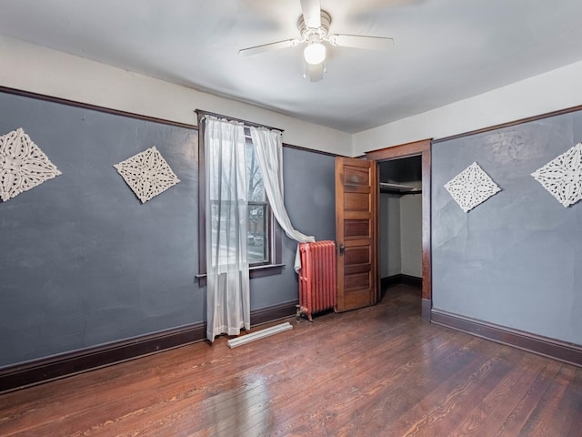 unfurnished bedroom with radiator heating unit, a closet, ceiling fan, and dark wood-type flooring