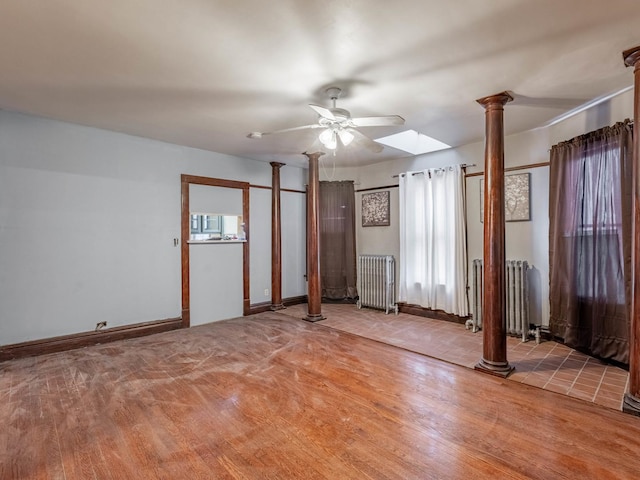 unfurnished room with decorative columns, radiator, ceiling fan, and hardwood / wood-style flooring