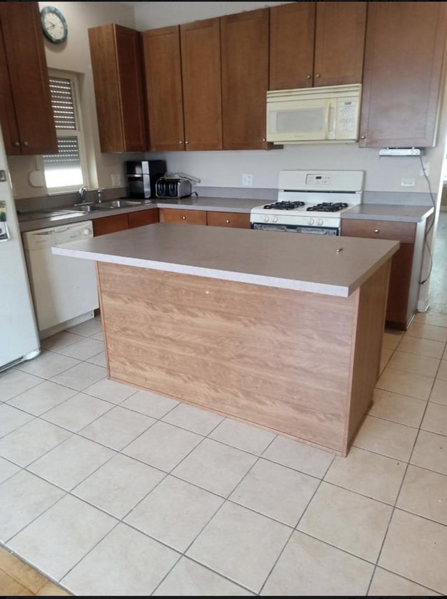 kitchen featuring light tile patterned flooring, white appliances, sink, and a kitchen island