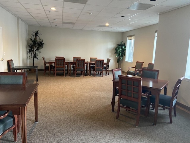 carpeted dining area with a drop ceiling