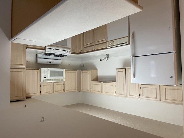 kitchen with light brown cabinetry and white microwave