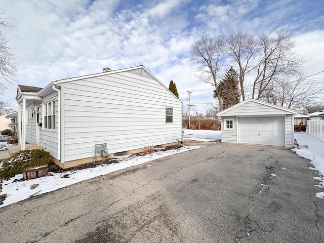 snow covered property featuring an outbuilding and a garage