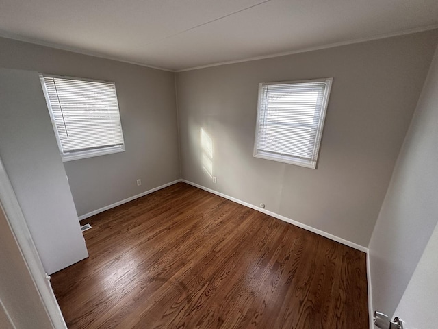 empty room with crown molding, a healthy amount of sunlight, and dark hardwood / wood-style floors