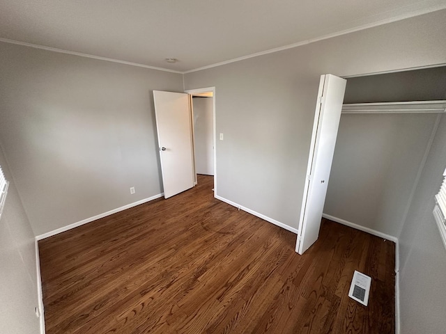 unfurnished bedroom with a closet, dark wood-type flooring, and ornamental molding