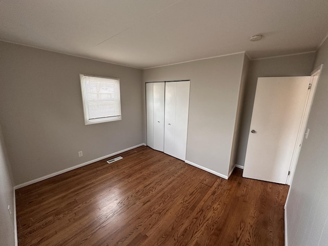 unfurnished bedroom featuring a closet and dark wood-type flooring