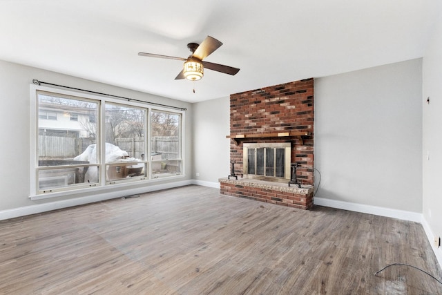 unfurnished living room featuring hardwood / wood-style floors, ceiling fan, and a brick fireplace