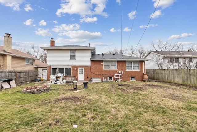 rear view of property with a yard and an outdoor fire pit