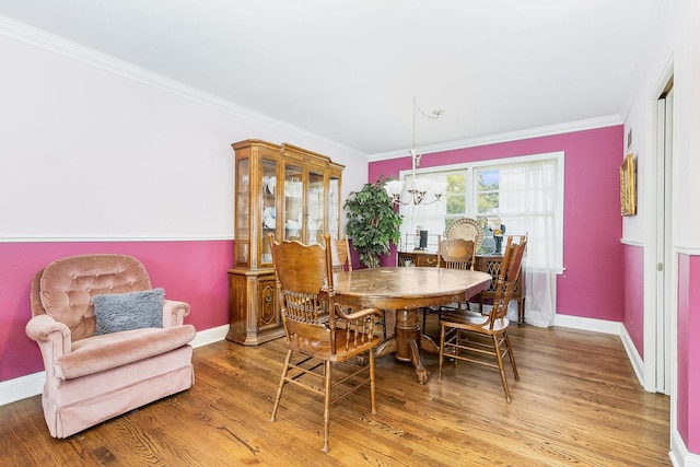 dining room featuring wood-type flooring, crown molding, and a notable chandelier