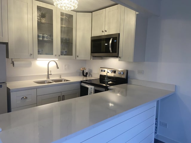 kitchen featuring white cabinetry, sink, a chandelier, and appliances with stainless steel finishes