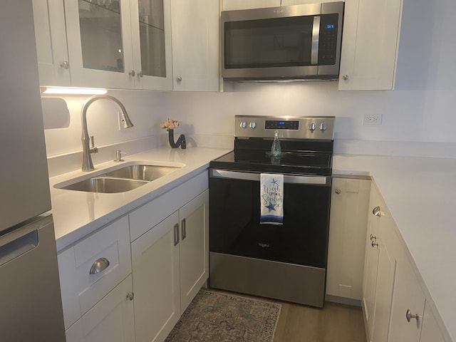 kitchen featuring dark hardwood / wood-style flooring, sink, white cabinetry, and stainless steel appliances