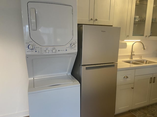 laundry area with stacked washer and clothes dryer and sink