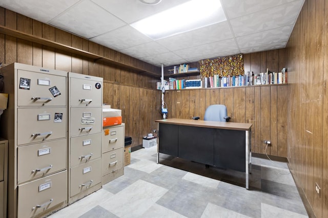 office space featuring a paneled ceiling and wood walls