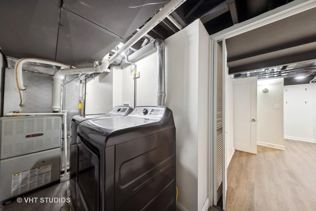 washroom with heating unit, hardwood / wood-style flooring, and independent washer and dryer