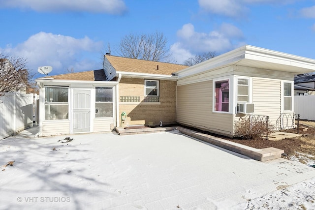 snow covered house with cooling unit and a patio