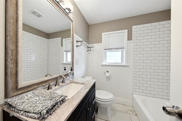 full bathroom featuring tiled shower / bath, vanity, and toilet