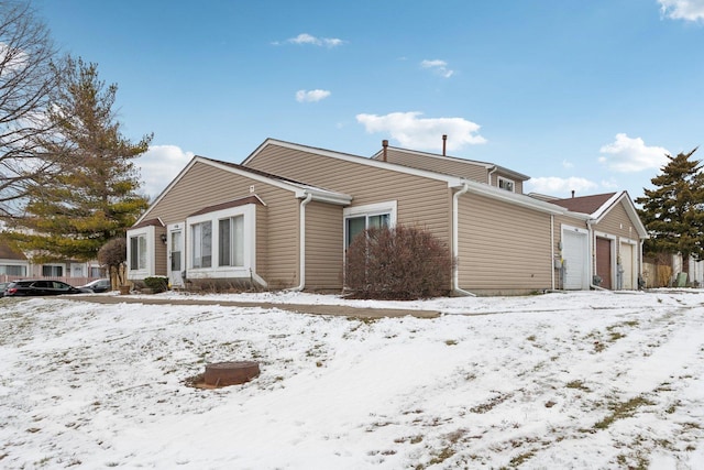 snow covered back of property featuring a garage