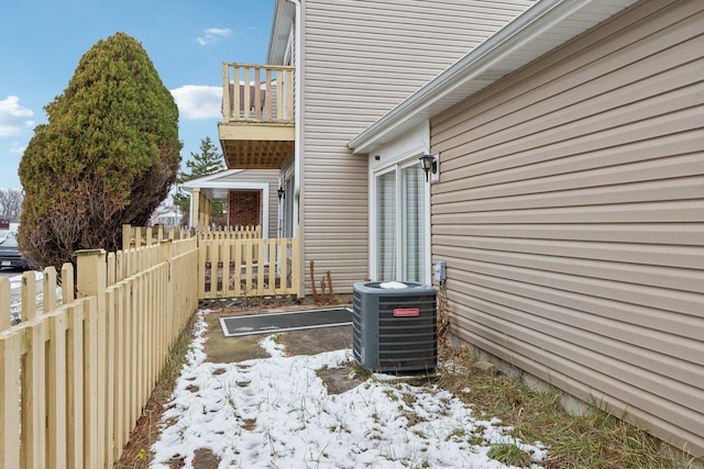 view of snow covered exterior featuring a balcony and central AC unit