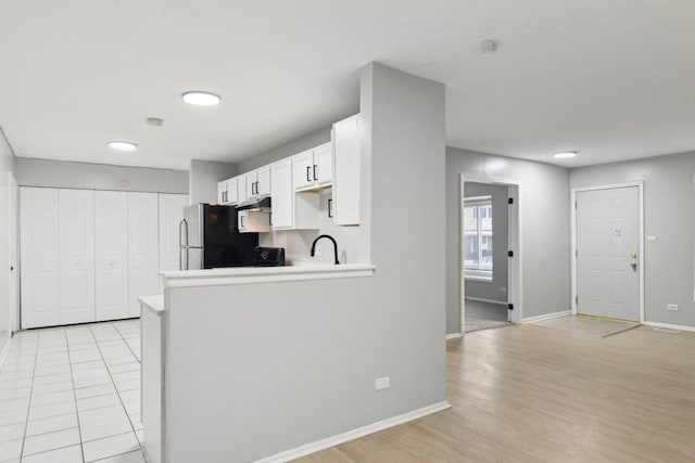 kitchen with sink, white cabinetry, stainless steel fridge, light hardwood / wood-style floors, and kitchen peninsula