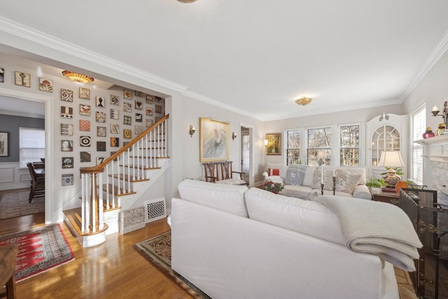 living room featuring hardwood / wood-style flooring, crown molding, and a stone fireplace