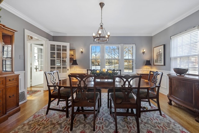 dining area with light hardwood / wood-style flooring, an inviting chandelier, and crown molding