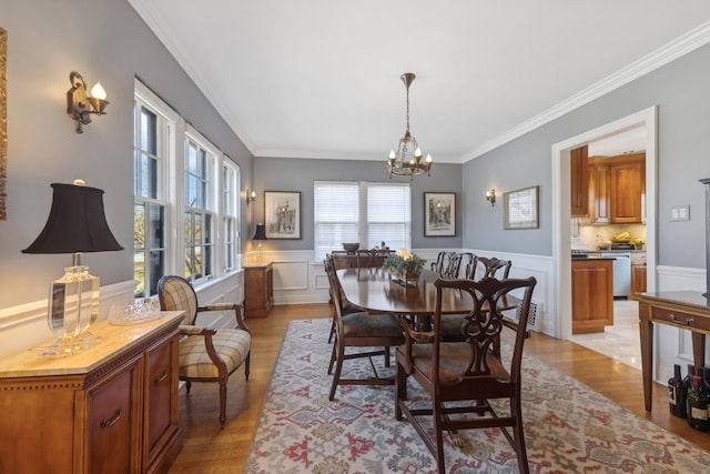 dining room with light wood-type flooring, a notable chandelier, and crown molding