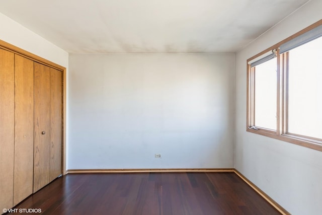 unfurnished bedroom with dark hardwood / wood-style floors and a closet