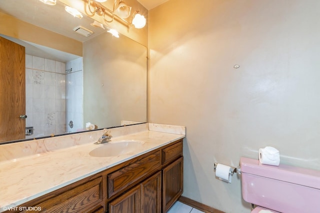 bathroom with tiled shower, vanity, and toilet