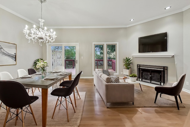 dining space with hardwood / wood-style flooring, crown molding, and a notable chandelier