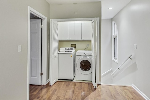 washroom with cabinets, light wood-type flooring, and washing machine and clothes dryer